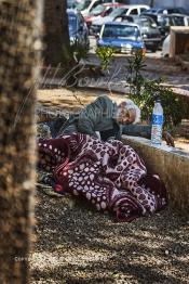 Image du Maroc Professionnelle de  Un des pèlerins installé à même le sol pour se purifier d'une malade auprès du saint, à gauche une partie du fameux mur clouté qui se trouvait à l'ouest de la koubba du saint Sidi Bousmara, située sur la place du même nom à Casablanca, Lundi 28 Avril 2009. La légende raconte qu’un vieux pèlerin à la barbe blanche drapé de blanc frappa alors le sol avec son bâton et une source jaillit du sol. il s’installe à Casablanca au milieu du cimetière et plante un caoutchouc qui devint rapidement gigantesque. Le saint marabout Sidi Bousmara est visité depuis longtemps par tous ceux qui sont atteint de la rage convergent vers ce lieu et plante un clou sur l’arbre dans l’espoir d’une guérison, ou sur le mur est.  (Photo / Abdeljalil Bounhar)

